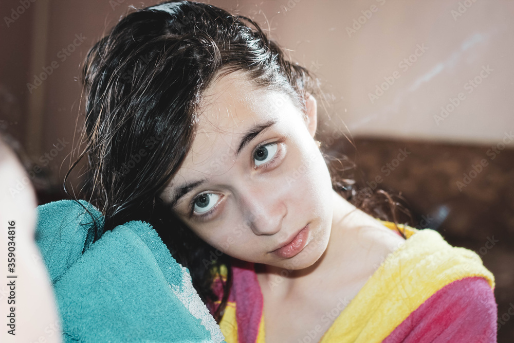 Φωτογραφία A beautiful 11-year-old girl wipes her wet hair with a towel in front of the mirror