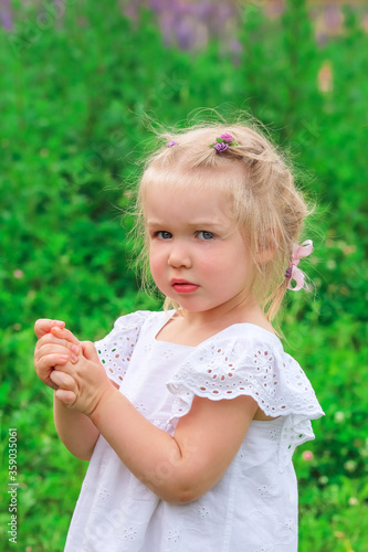 Portrait of a beautiful little blonde girl in nature