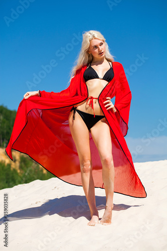 Sexy young beautiful blonde girl in black bikini and red tunic