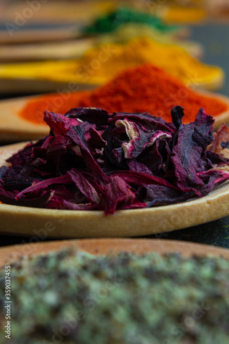 spice background on wooden spoons. Seasoning texture. Hibiscus, black pepper, paprika, cumin, curry, parsley
