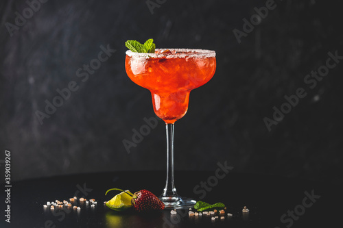 Foto Frozen strawberry lime mint margarita in tall footed glass on the dark background