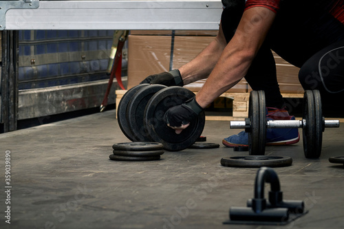 Man preparing the dumbbells for training in a warehouse.