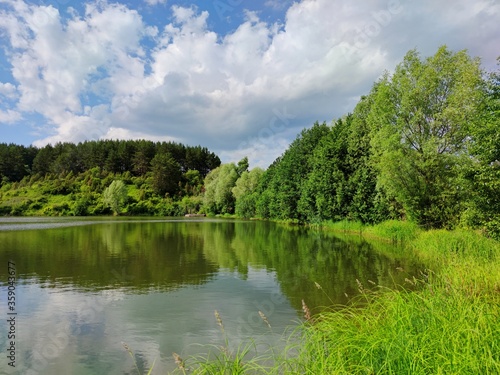 beautiful reflection of trees in the pond water against the background of a wonderful blue sky with clouds © Sergey Egovkin