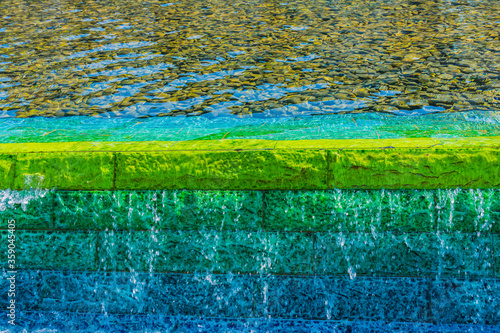 Bright fountain water on a green and blue wall with sun reflection background, Zabeel Park, Dubai, United Arab Emirates