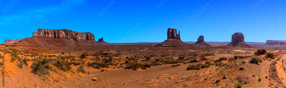 A panorama view showing Elephant Butte, East and West Mitten Buttes in Monument Valley tribal park in springtime