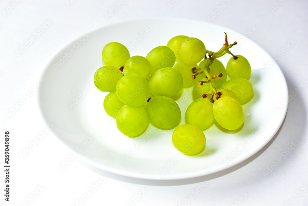 Green delicious ripe grapes on a white plate Green delicious ripe grapes on a white plate