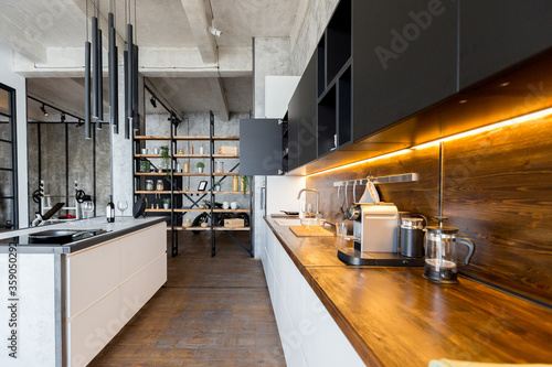 luxury studio apartment with a free layout in a loft style in dark colors. Stylish modern kitchen area with an island, cozy bedroom area with fireplace and personal gym