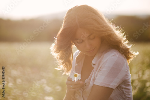 Young beautiful woman relaxing in chamomile field.