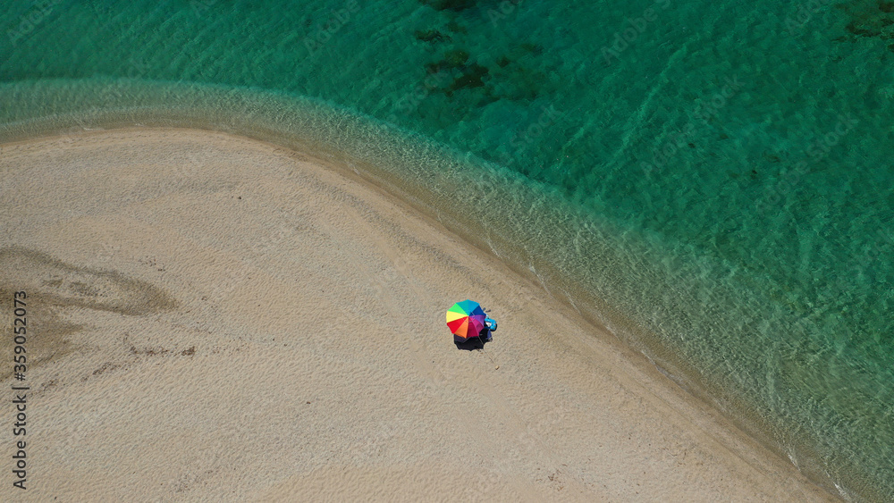Obraz premium Aerial top down photo of beautiful turquoise Mediterranean secluded sandy bay forming a small peninsula with only one colourful sun umbrella enjoying summer