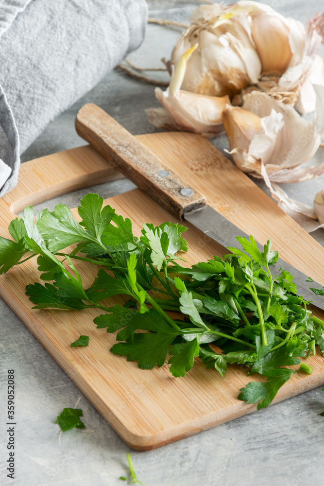 Cooking with greenery, fresh raw parsley and garlic on kitchen table Cooking with greenery, fresh raw parsley and garlic on kitchen table