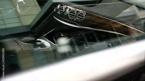 A shot through the glass of a wooden dashboard of an expensive business class car.