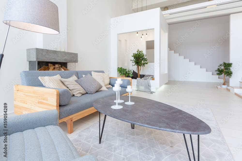 Fototapeta premium Luxury fashionable modern design studio apartment with a free layout in a minimal style. very bright huge spacious room with white walls and wooden elements. sitting area with fireplace