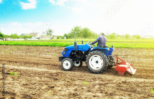Farmer on a tractor with milling machine loosens, grinds and mixes soil. Field preparation for new crop planting. Work on preparing the soil for a sowing of seeds of agricultural crops.