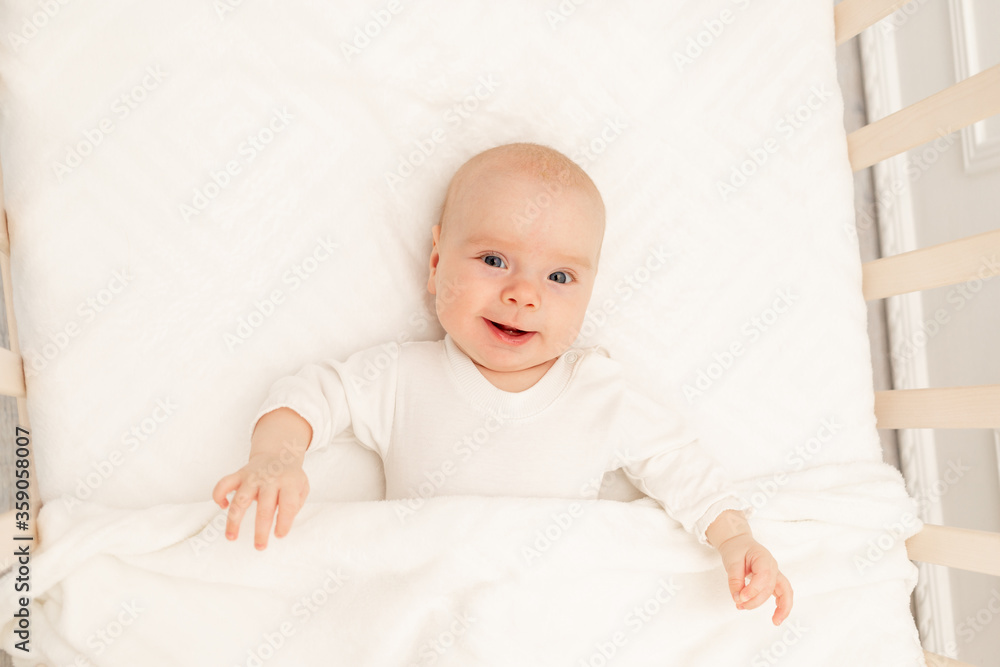Sleeping baby and his toy in white crib. Nursery interior and bedding for kids. Cute little boy napping in bassinet. Kid taking a nap in white bedroom. Healthy child in bodysuit pajamas.