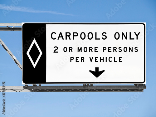 Overhead freeway carpool only sign with blue sky.
