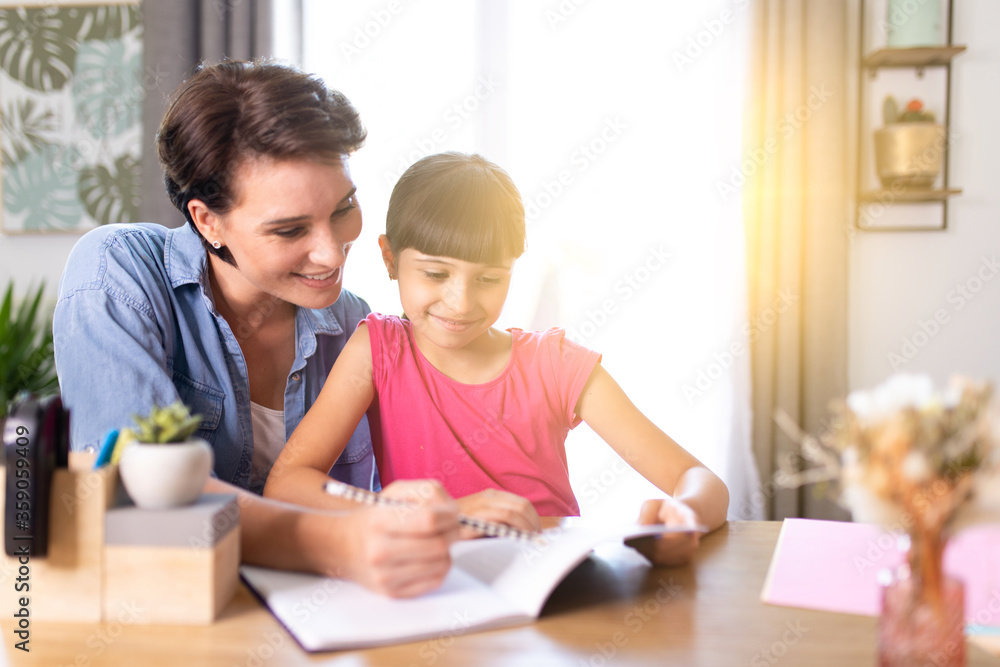 a smiling mother helping her daughter understand homework at home a smiling mother helping her daughter understand homework at home