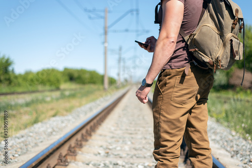 Traveler with mobile phone in hands is waiting for a train.