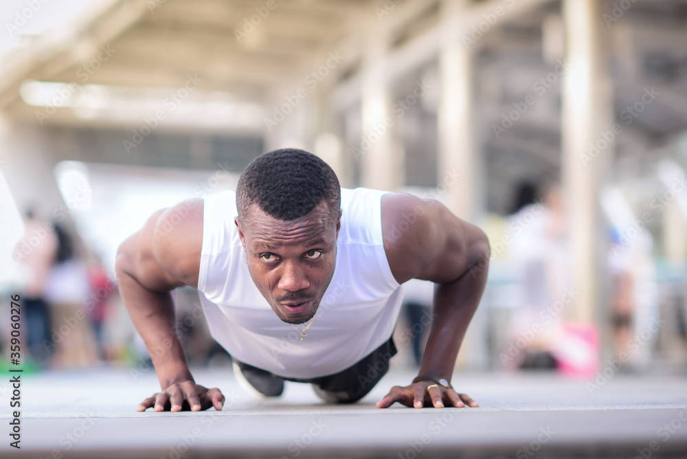 Fototapeta premium African american man is outdoor exercising by push up Look strong, clearly see the muscles in the upper arm