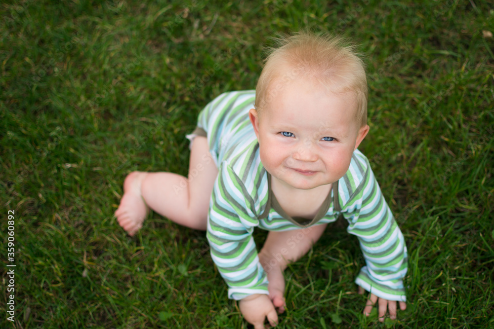 cute little baby sitting on the green grass and looking upwards, topview cute little baby sitting on the green grass and looking upwards, topview