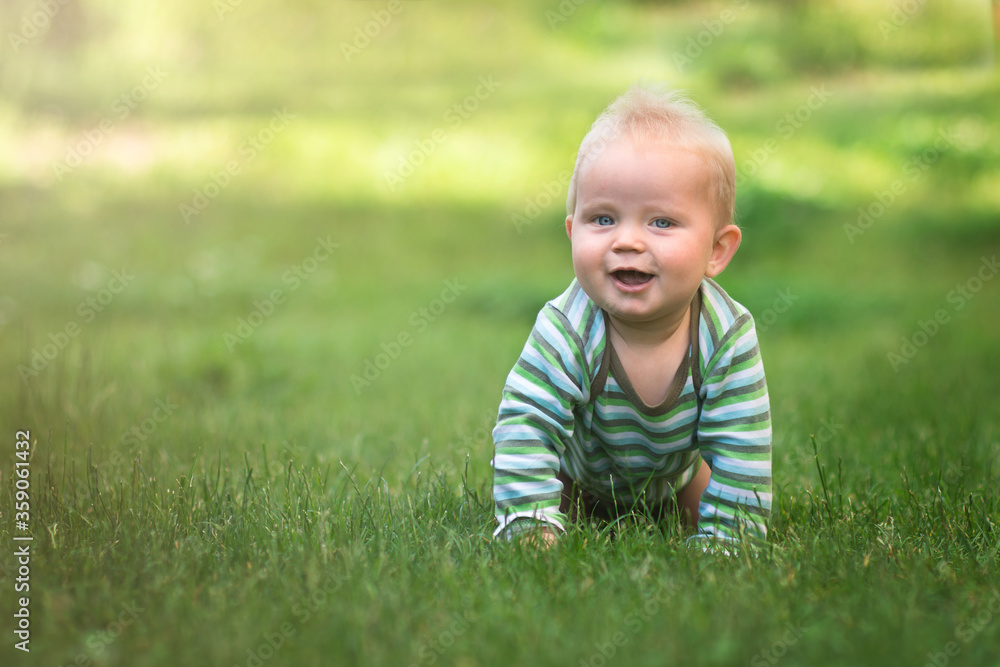 nine month baby crawl on all fours on green grass and smile, banner copy space, kid connect with the nature