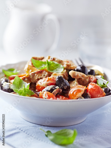 Penne pasta baked with pork tenderloin, cherry tomatoes, black olives and cheese. Close up.