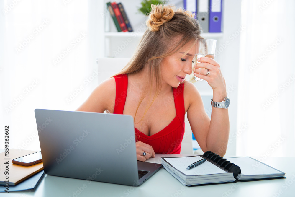 Young woman sitting in office at computer with a glass of clean water. Drinking plenty is the key to health, helps with stress and fatigue in business Young woman sitting in office at computer with a glass of clean water. Drinking plenty is the key to health, helps with stress and fatigue in business