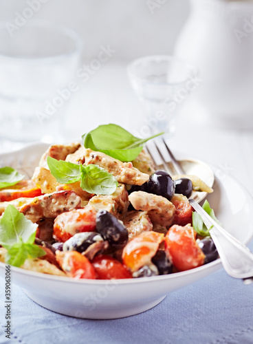 Penne pasta baked with pork tenderloin, cherry tomatoes, black olives and cheese. Close up.