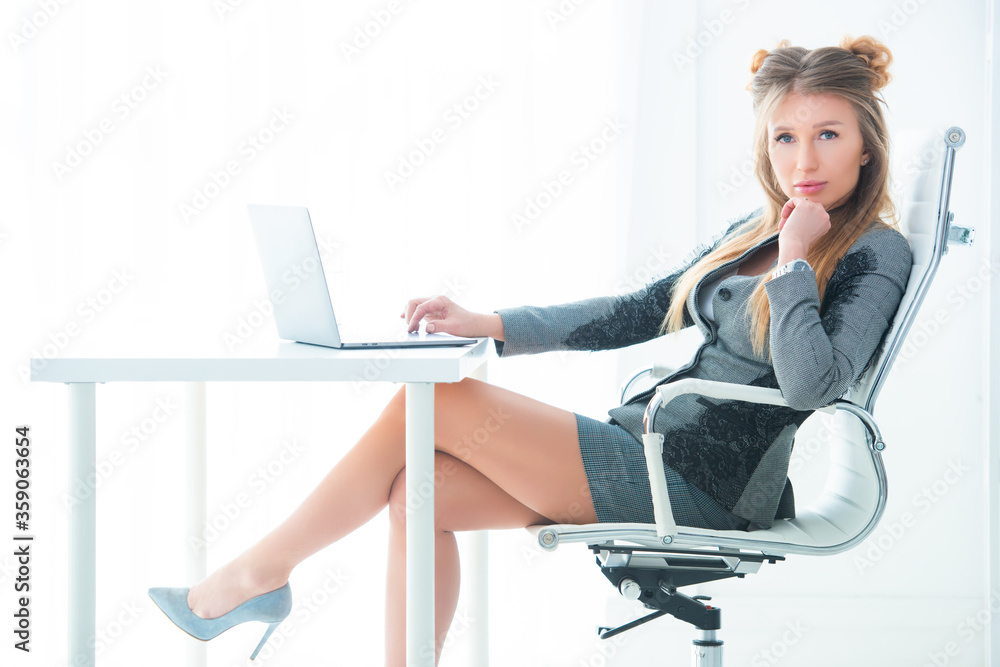 Business woman in a strict business suit works in an office at a desk on a laptop Business woman in a strict business suit works in an office at a desk on a laptop