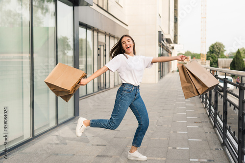 Happy beautiful woman with shopping bags in hand cheerfully jumping in the air.