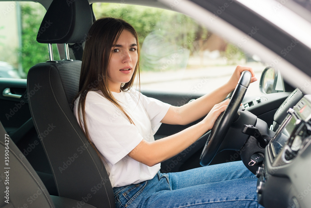 Naklejka premium Young woman hand pressing the horn button while driving a car through the road.