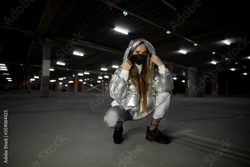 Fashionable young woman in mask at the undreground parking of mall. Pandemic woman concept photo