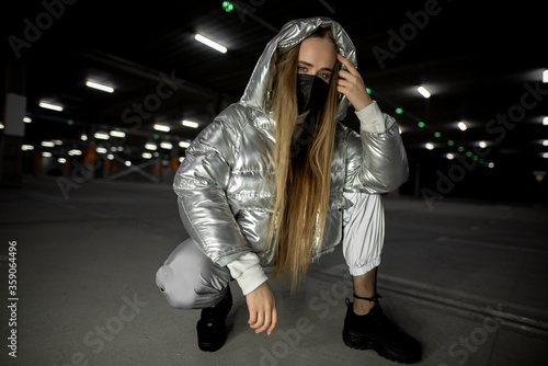 Fashionable young woman in mask at the undreground parking of mall. Pandemic woman concept photo