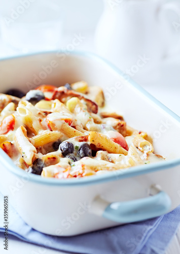 Penne Pasta baked with Vegetables on bright wooden Background. Close up. 