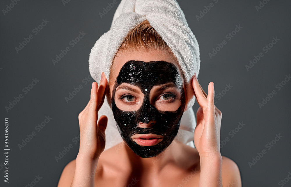 Beautiful woman with black peel-off mask on a gray background. Beautiful woman with black peel-off mask on a gray background.
