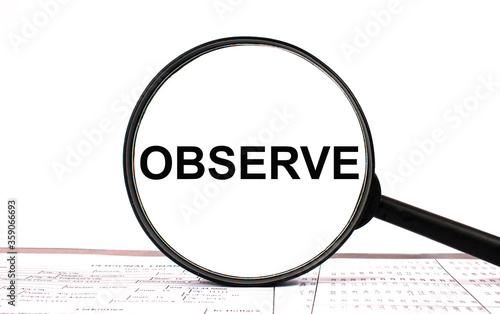 Magnifying glass with text OBSERVE on financial tables