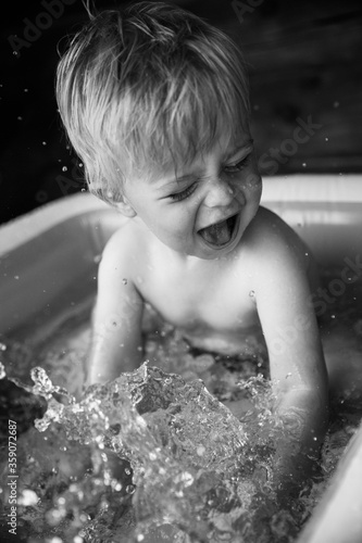Toddler boy having fun in inflatable swimming pool