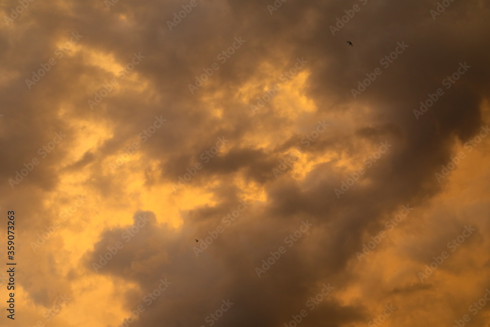 Full frame of dark weather clouds in the orange sky