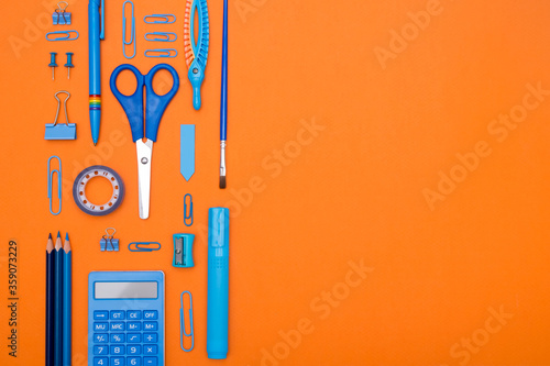 Back to School concept. Top view school supplies on a student desk on orange background. Flat lay and copy space.