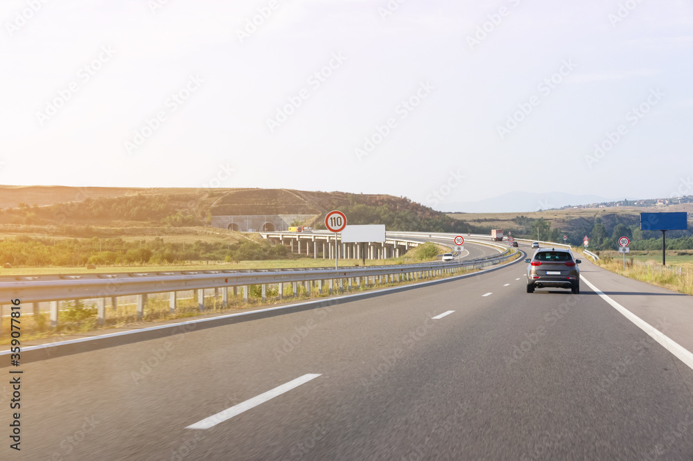 crossover car driving fast on asphalt road. the road in front of the tunnel. speed limit signs crossover car driving fast on asphalt road. the road in front of the tunnel. speed limit signs