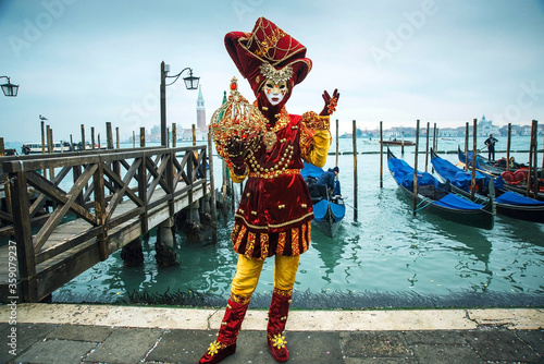Beautiful colored carnival costume on the street in Venice. Carnival of Venice. Woman in purple dress near sea and gondola