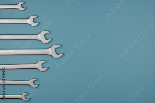 Set chrome spanner keys lying side by side on blue background. Flat lay, top view, minimal composition with copy space