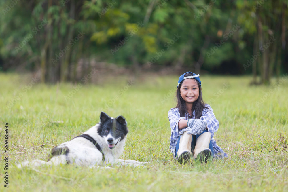 A cute Asian girl is sitting happily with her dog on the lawn A cute Asian girl is sitting happily with her dog on the lawn