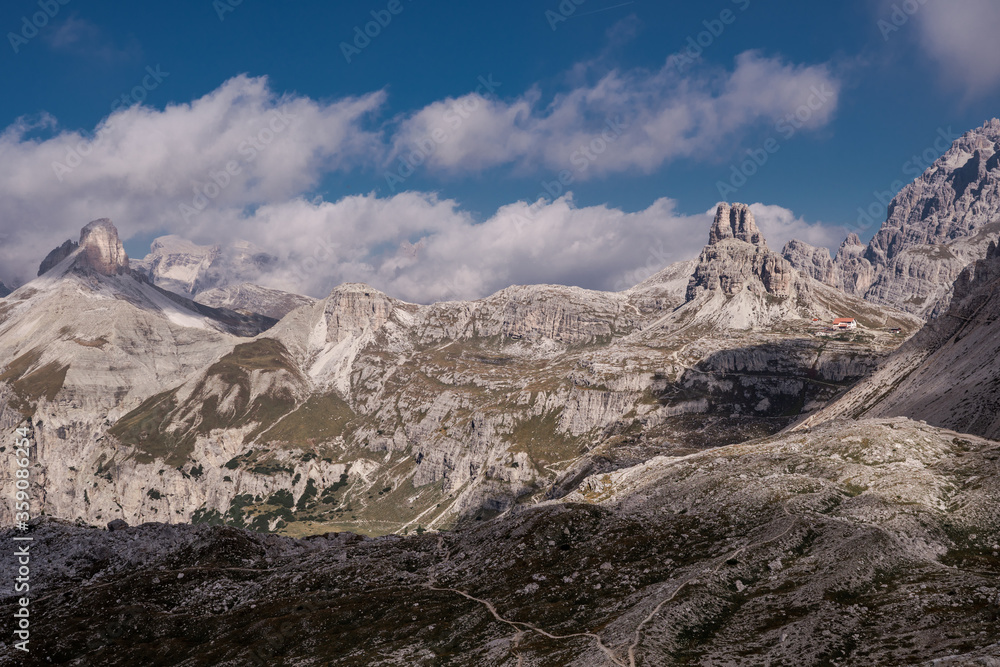 Dolomites Alps. Italy. Desert view from Tre Cime di Lavaredo. Alpine valley with canyon & dolomite peaks on background of blue sky and white clouds