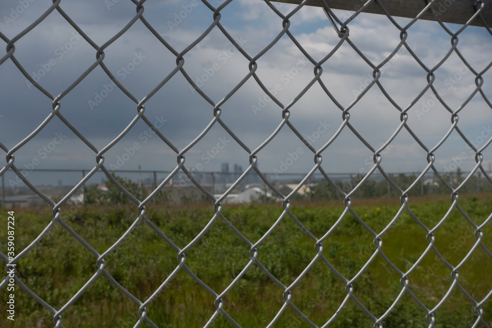 Fototapeta premium Chain Link Mesh Fence with calgary skyline in distance