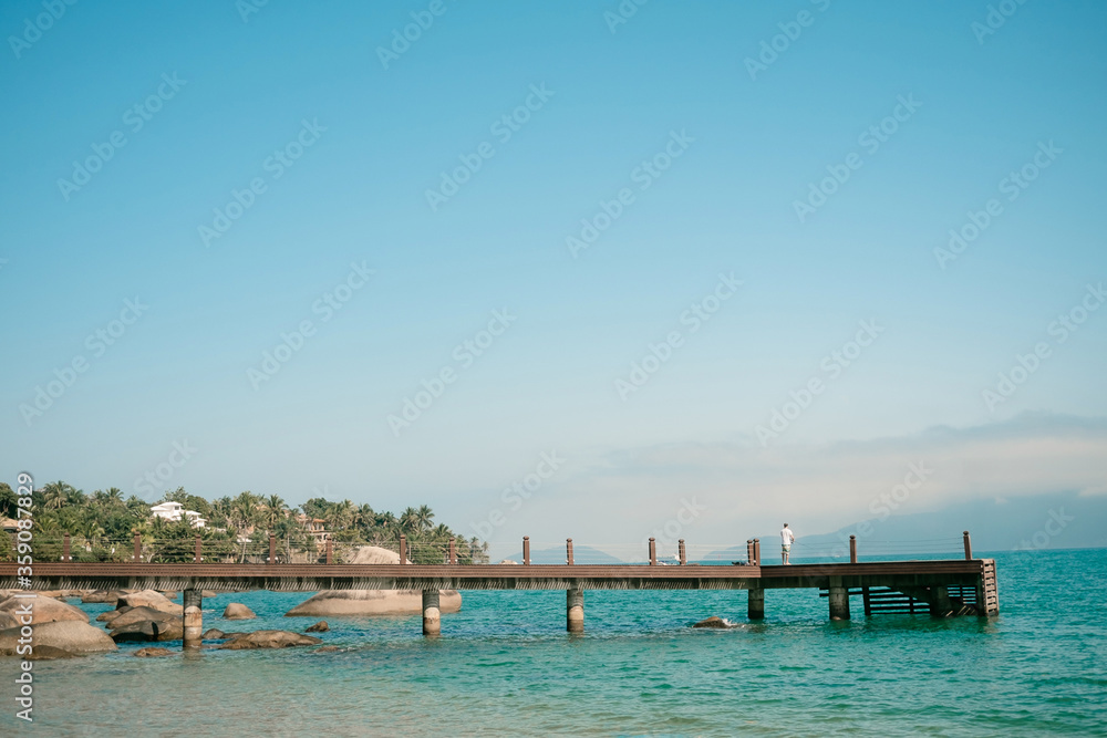 Foto panorâmica de um pier com um pescador na praia da feiticeira em Ilhabela, litoral norte de são paulo.