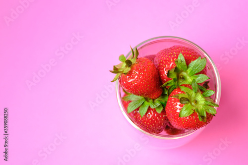 Strawberries are juicy in a bowl. On a pink background.