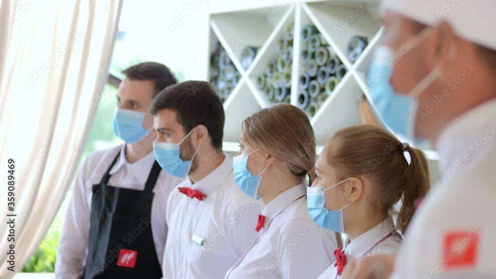 Employees of a restaurant in protective masks after quarantine. Interaction with restaurant manager and his staff on the terrace Employees of a restaurant in protective masks after quarantine. Interaction with restaurant manager and his staff on the terrace