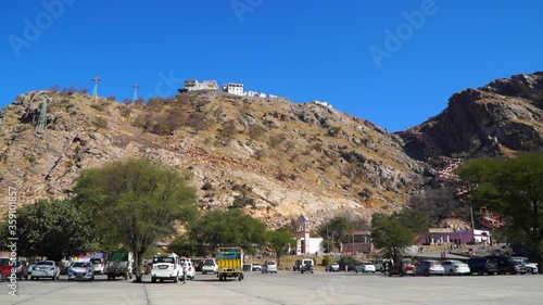 15 February 2020 : Chomu , Rajasthan, India / Top view of the Veer Hanuman Ji Temple. Crowd of people walking on the mountain and road. Car parking area. A lot of cars and buses parked at parking area