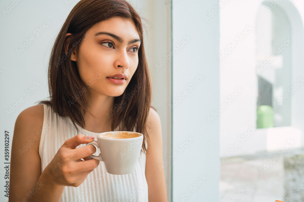 Young woman drinking a cup of coffee at coffee shop. Young woman drinking a cup of coffee at coffee shop.