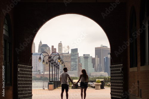 Young couple together holding their hand while their are walking around the New York City with a cloudy weather.
